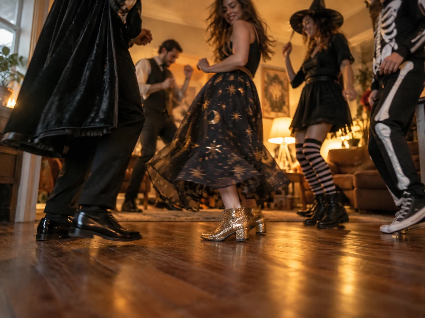 Costumed adults dancing at a warmly lit Halloween party